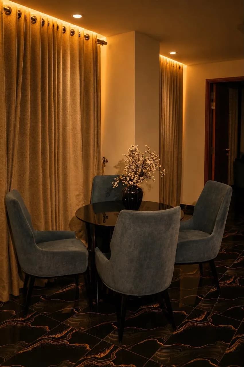 In-suite dining nook with a round black table and four upholstered chairs
