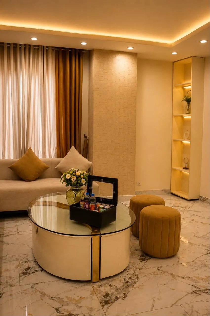 Sitting room with a round mirrored table, ochre stools and veined marble flooring