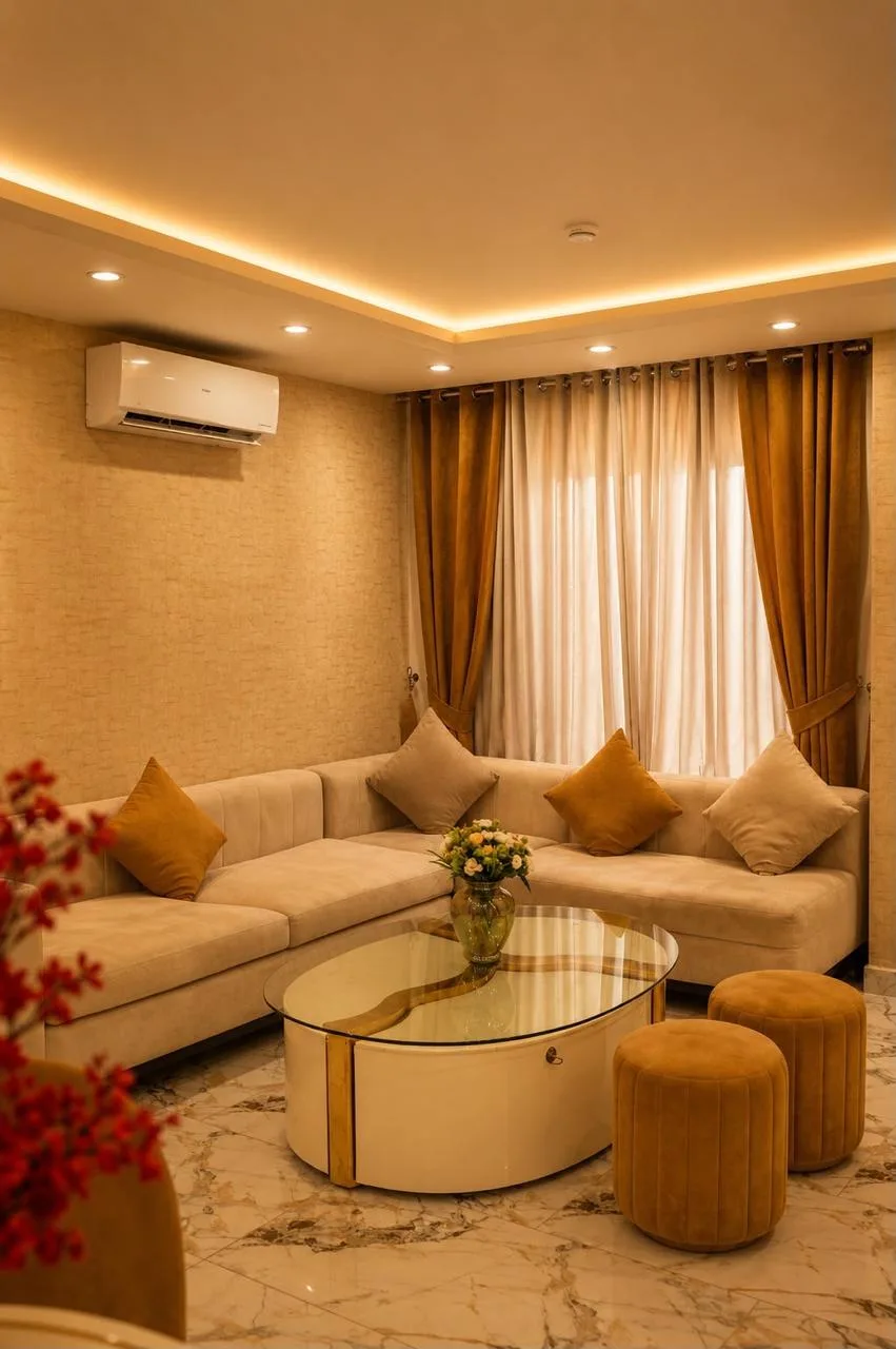 Lounge with gold curtains, a beige sectional and a mirrored coffee table